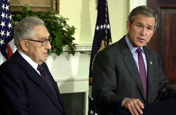 Former president George W. Bush speaks alongside Henry Kissinger prior to signing a bill to create an independent commission to investigate the attacks on the World Trade Center and the Pentagon, and the years leading up to them, in the Roosevelt Room at the White House in 2002. (Ron Sachs-Pool/Getty Images)
