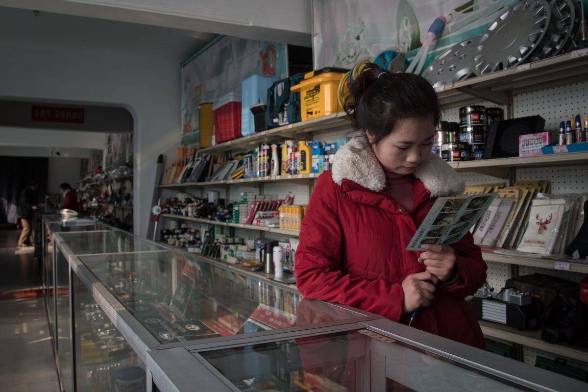 A sales assistant looks at a leaflet as she waits for customers at a vehicle parts shop in Pyongyang, North Korea, on Nov. 16, 2017. Women face violence and sexual abuse in North Korea without hope of police or other authorities punishing the perpetrators. (ED JONES/AFP/Getty Images)