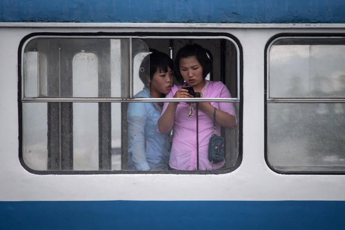 In this photo taken on June 6, 2017, women look at a mobile phone as they ride a tram in Pyongyang. (ED JONES/AFP/Getty Images)