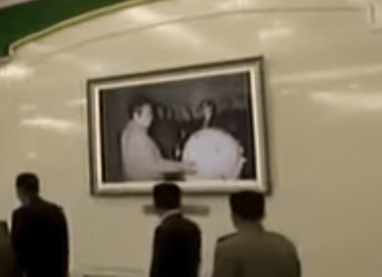 Former North Korean leader Kim Jong Il inspects what could be a miniaturized atomic bomb in a photograph hanging in Pyongyang, North Korea, Dec. 11, 2017. (Screenshot via Stimme Koreas/YouTube)
