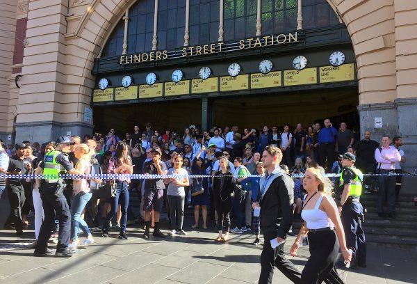 Members of the public stand behind police tape after Australian police said on Thursday they have arrested the driver of a vehicle that ploughed into pedestrians at a crowded intersection near the Flinders Street train station in central Melbourne, Australia Dec. 21, 2017. (Reuters/Melanie Burton)