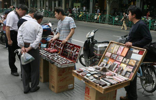 Street vendors sell counterfeit watches and fake luxury brand wallets outside a department store in Shanghai, China, on May 23, 2007. (Mark Ralston/AFP/Getty Images)