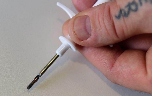 An employee of internet security company Kaspersky Lab shows a syringe fitted with a microchip during a Kaspersky Lab press conference on biological, psychological and technological implications of microchip implants ahead of the opening of the 55th IFA (Internationale Funkausstellung) electronics trade fair in Berlin on Sept. 3, 2015. (John MacDougall/AFP/Getty Images)
