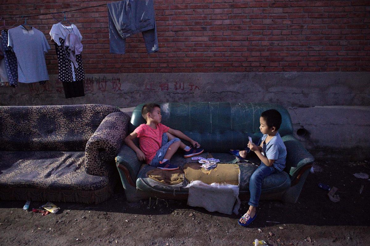 Boys play cards at night in a migrant village on the outskirts of Beijing on Sept. 7, 2017. (Nicolas Asfouri/AFP/Getty Images)