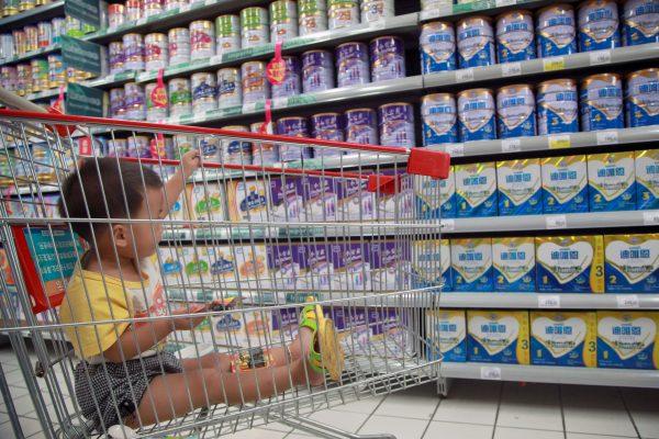 A baby in a shopping cart as his mother selects baby milk at a supermarket in Haikou, in south China's Hainan Province, on Aug. 7, 2013. (STR/AFP/Getty Images)