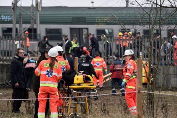 Rescue workers and police officers stand near derailed trains in Pioltello, on the outskirts of Milan, Italy, Jan. 25, 2018. (Reuters/Stringer)