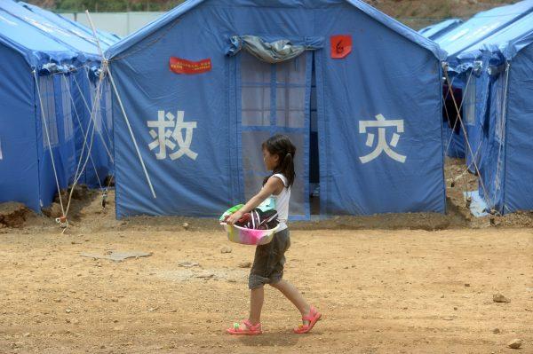 A little girl carrying laundry at a temporary shelter in Longtoushan township in Ludian County following the earthquake, on Aug. 7, 2014. (AFP/AFP/Getty Images)