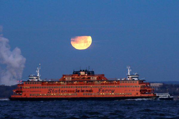 The "Super Blue Blood Moon" sets behind the Staten Island Ferry, seen from Brooklyn, New York, U.S., Jan. 31, 2018. (Reuters/Eduardo Munoz)