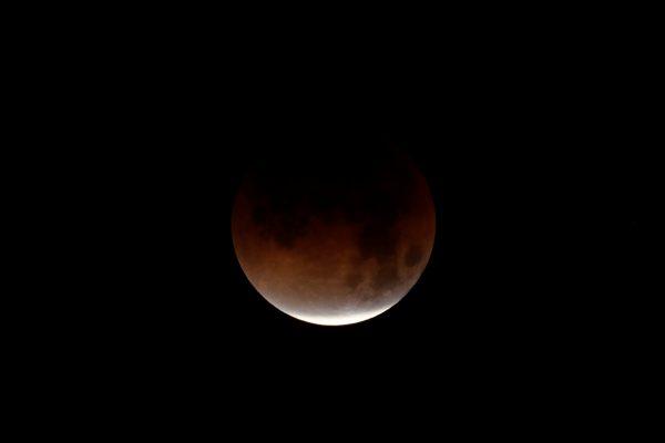 A lunar eclipse is shown over the ocean in Oceanside, California, U.S., Jan. 31, 2018. (Reuters/Mike Blake)