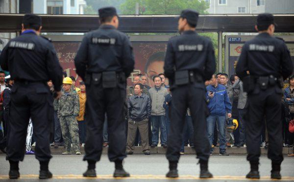 Citizens watch as police stand guard outside the Xianning Intermediate People's Court where Liu Han stood trial in Xianning City, central China's Hubei Province on March 31, 2014. (STR/AFP/Getty Images)