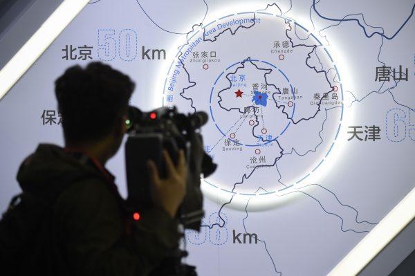A journalist takes a video in front of a map of Beijing and Hebei Province on Oct. 22, 2017. (Wang Zhao/AFP/Getty Images)