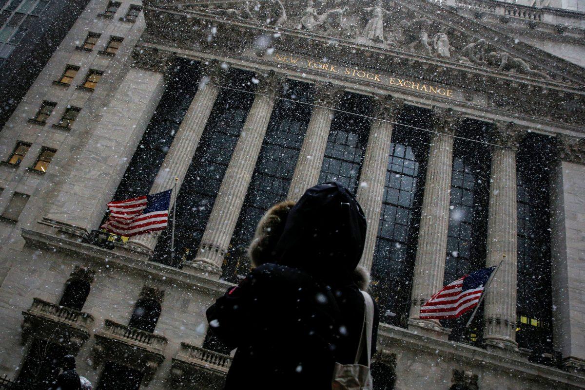 A woman stops to photograph the New York Stock Exchange as snow begins to fall during the morning commute in New York City, on Feb. 7, 2018. (Brendan McDermid/Reuters)