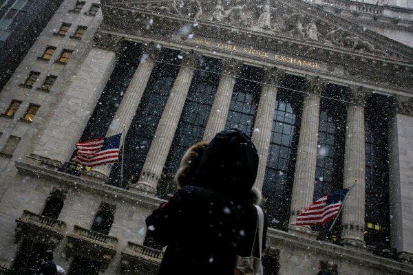 A woman stops to photograph the New York Stock Exchange as snow begins to fall during the morning commute in New York City, U.S., Feb. 7, 2018. (Reuters/Brendan McDermid)
