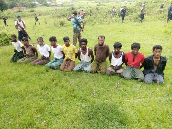 Ten Rohingya Muslim men with their hands bound kneel as members of the Myanmar security forces stand guard in Inn Din village Sept. 2, 2017. (Handout via Reuters)