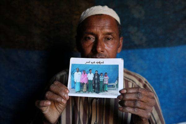 Abdu Shakur, whose son Rashid Ahmed was among 10 Rohingya men killed by Myanmar security forces and villagers on Sept. 2, 2017, holds a family picture at Kutupalong camp in Cox's Bazar, Bangladesh, Jan. 19, 2018. (Reuters/Mohammad Ponir Hossain)