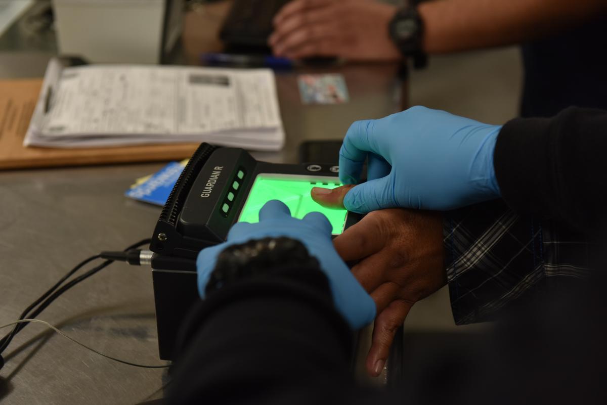 Immigration officers fingerprint an illegal alien during a targeted enforcement operation in Los Angeles on Feb. 11, 2018. (ICE)