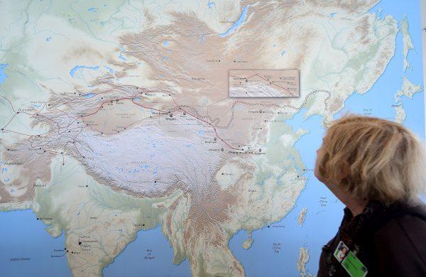 A woman walks past a map of China and Central Asia with a red line signifying the ancient trade route known as the Silk Road, at the Getty Center in Los Angeles, United States, on May 9, 2016. (Frederic J. Brown/AFP/Getty Images)
