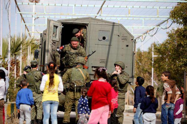 Russian soldiers are seen with Syrian children at Wafideen camp in Damascus, Syria Feb. 28, 2018. (Reuters/Omar Sanadiki)