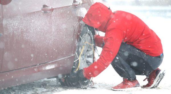 A man places snow chains on his tyres in Leek, Britain, March 1, 2018. (Reuters/Carl Recine)
