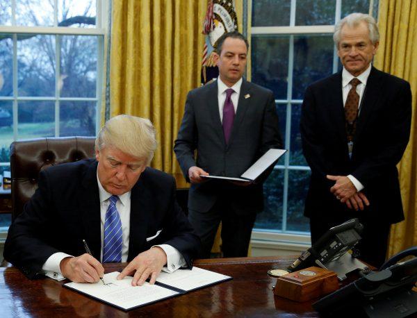 U.S. President Donald Trump signs the executive order for the reinstatement of the Mexico City Policy in the Oval Office of the White House in Washington on Jan. 23, 2017. With Trump (L-R) are then White House Chief of Staff Reince Priebus and head of the White House Trade Council Peter Navarro. (Reuters/Kevin Lamarque/Files)