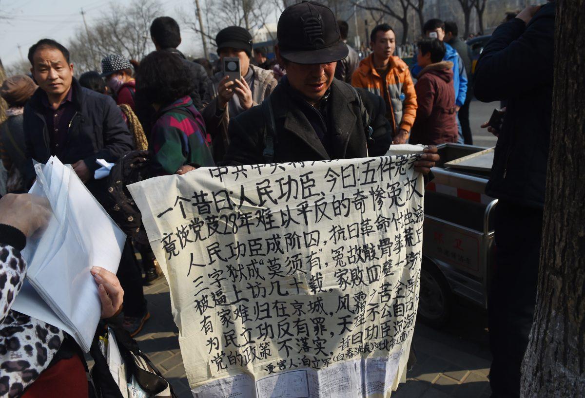A man holds a protest banner outside the central petition office in Beijing on March 2, 2016. (Greg Baker/AFP/Getty Images)