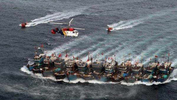 A picture taken on Nov. 16, 2011 from a South Korean helicopter shows Chinese boats banded together with ropes, chased by a coastguard helicopter and rubber boats pacted with commandoes, after alleged illegal fishing in South Korean waters in the Yellow Sea off the southwestern coast county of Buan. South Korea's coastguard mobilised 12 ships, four helicopters and commandoes for a special three-day crackdown on illegal fishing by Chinese boats this week.<br/>(DONG-A ILBO/AFP/Getty Images)