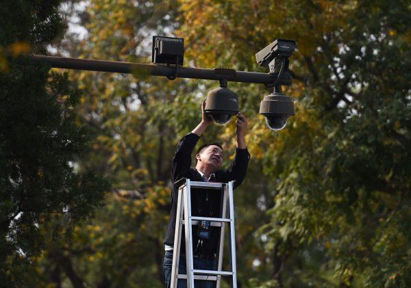 A worker adjusts security cameras on the edge of Tiananmen Square in Beijing on Sept. 30, 2014. (Greg Baker/AFP/Getty Images)