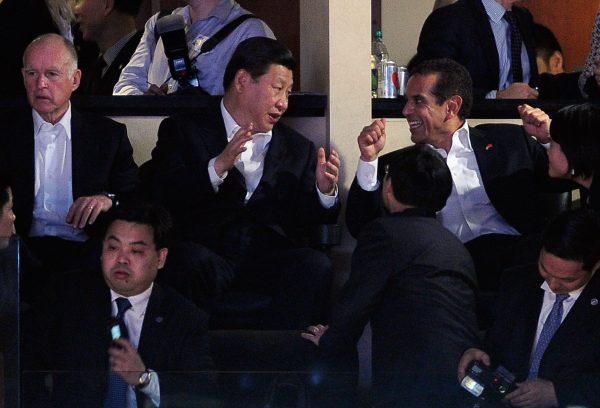 Xi Jinping (C), with California Governor Jerry Brown (L) and then-Los Angeles Mayor Antonio Villaraigosa (R) attend the Los Angeles Lakers and Phoenix Suns NBA basketball game at Staples Center in Los Angeles, California on February 17, 2012. Zhong Shaojun is sitting in the row in front, looking ahead with a cell phone in hand. (Kevork Djansezian/Getty Images)
