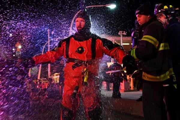 A FDNY rescue diver is hosed off with fresh water after pulling victims from a submerged helicopter after it crashed into the East River in New York, U.S., March 11, 2018. (Reuters/Darren Ornitz)