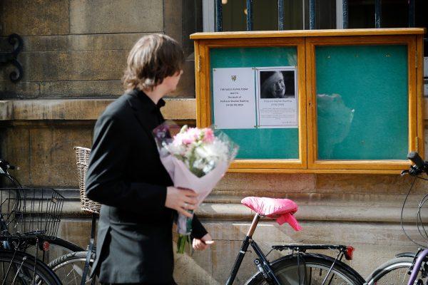 A man prepares to lay flowers outside Gonville and Caius College, at Cambridge University in Cambridge, on March 14, 2018, floowing the death of physicist Stephen Hawking, who was a fellow of the University for over 50 years. (Tonga Akmen/AFP/Getty Images)
