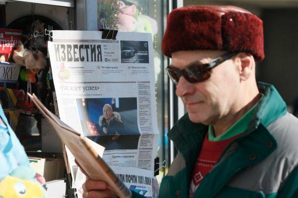 A man walks past a rack which displays a daily newspaper with a front page about Russian President Vladimir Putin’s re-election victory on March 18, on a street in Moscow, Russia March 19, 2018. (Reuters/Gleb Garanich)