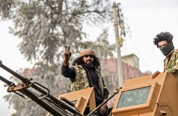 Turkish-backed Syrian Arab fighters stand on an armed vehicle after seizing control of Afrin on March 18, 2018. (Bulent Kilic/AFP/Getty Images)