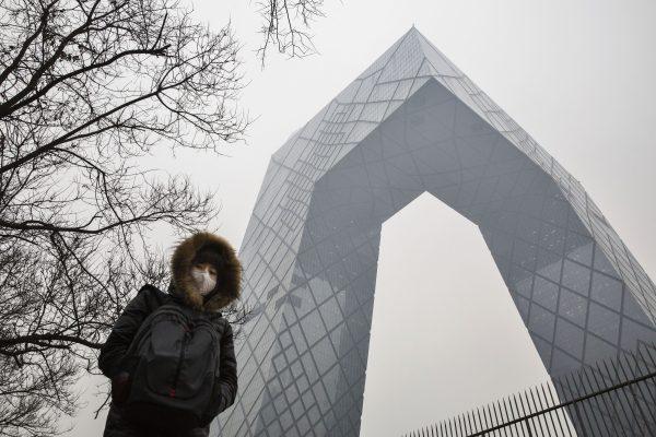 A Chinese woman passes the CCTV building in Beijing, China on December 8, 2015. (Kevin Frayer/Getty Images)