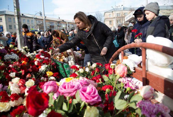 People place flowers at a makeshift memorial for the victims of a shopping mall fire in the Siberian city of Kemerovo, Russia March 26, 2018. (Reuters/Maksim Lisov)