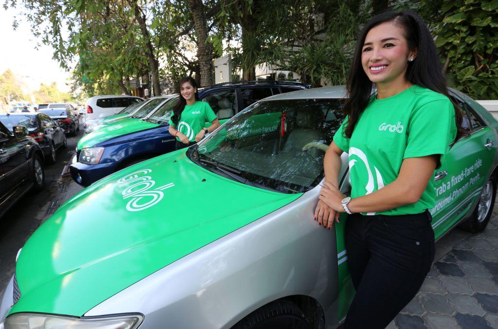 Models stand beside Grab cars during the launch of the ride hailing-firm's services in the country, in Phnom Penh on December 19, 2017.<br/>(Charly Two/AFP/Getty Images)