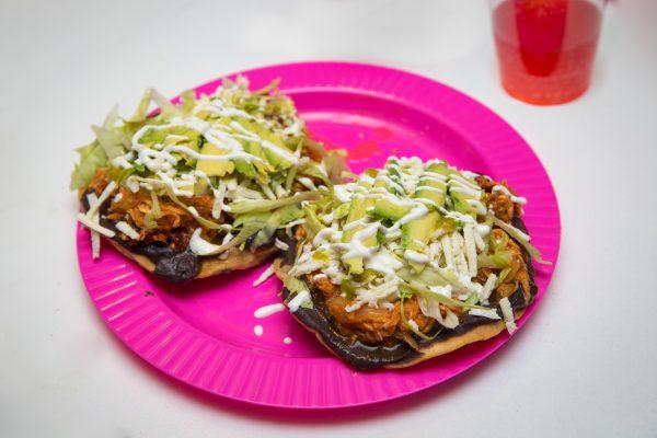 Tostadas with layers of refried black beans, chipotle-spiced chicken tinga, salsa roja, crema, queso fresco, and avocado slices. (Benjamin Chasteen/The Epoch Times)