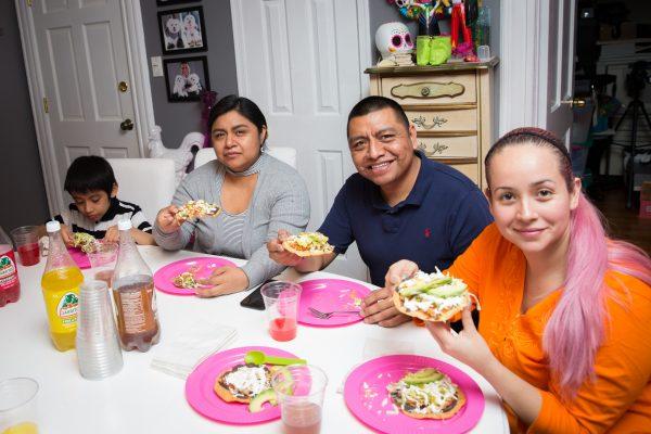 Angie Vargas (R) and her family enjoy Tostadas de Tinga (shredded spicy chicken tostadas). (Benjamin Chasteen/The Epoch Times)