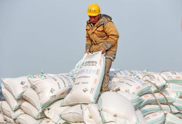 A Chinese worker carries a bag of soybean meal at a port in Nantong City, in China's eastern Jiangsu Province on March 22, 2018. (AFP/Getty Images)