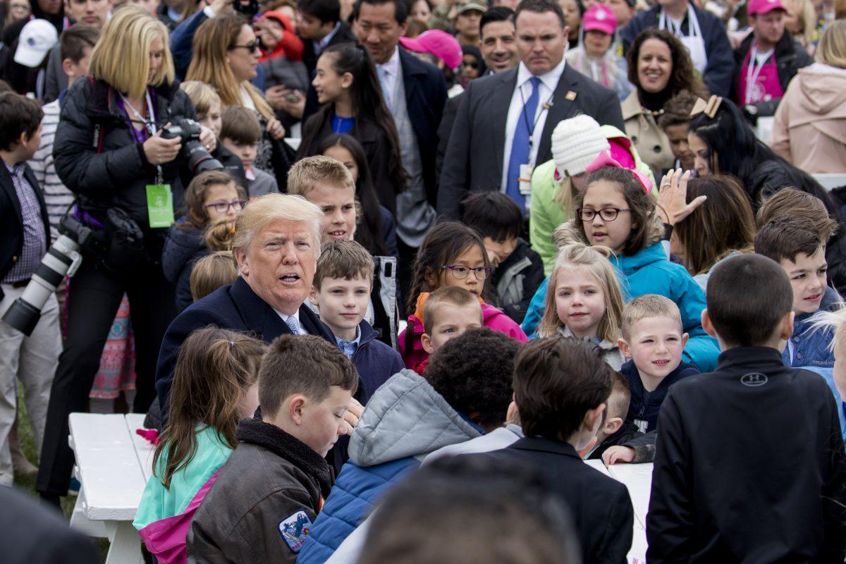 President Donald Trump sits with children as they write messages to military troops at the annual Easter Egg Roll on the South Lawn of the White House on April 2, 2018. (Samira Bouaou/The Epoch Times)