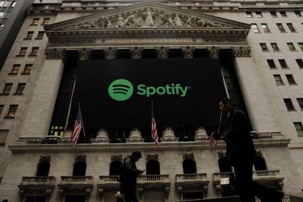 Pedestrians walk past a banner with the Spotify logo on it as the company lists its stock on the New York Stock Exchange with a direct listing in New York, U.S., April 3, 2018. (Reuters/Lucas Jackson)