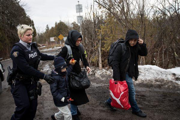 A family of three is escorted to a police vehicle by an RCMP officer after they illegally crossed the U.S.-Canada border into Hemmingford, Quebec in Canada, on Feb. 23, 2017. In the past month, hundreds of people have crossed Quebec land border crossings in attempts to seek asylum and claim refugee status in Canada. (Photo by Drew Angerer/Getty Images)