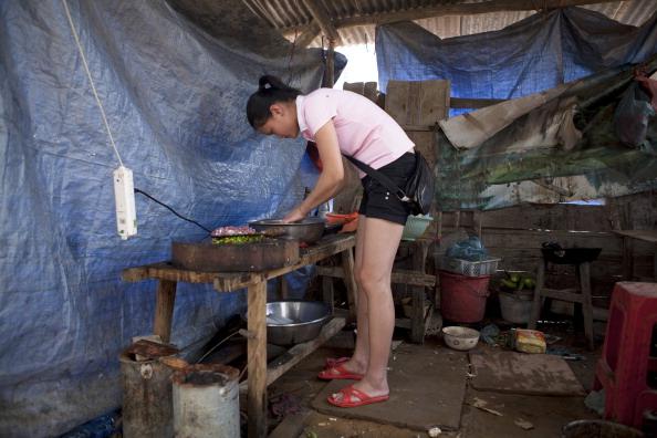 A woman who was evicted from her home to make way for the Loudi City Construction and Investment Co.-financed sports stadium cooks in a shelter used as a kitchen in Hunan Province, China, on June 17, 2011. (Adam Dean/Bloomberg via Getty Images)