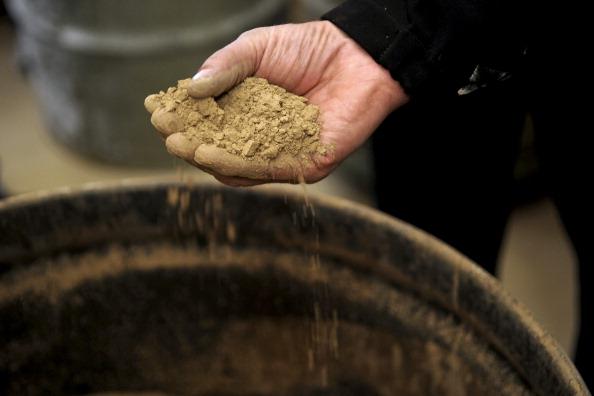 Rocky Smith, plant manager of Molycorp Inc. Mountain Pass rare earths mining and processing facility, holds a handful of rocks containing rare earth elements during a media tour in Mountain Pass, Calif., on Dec. 13, 2010. (Jacob Kepler/Bloomberg via Getty Images)