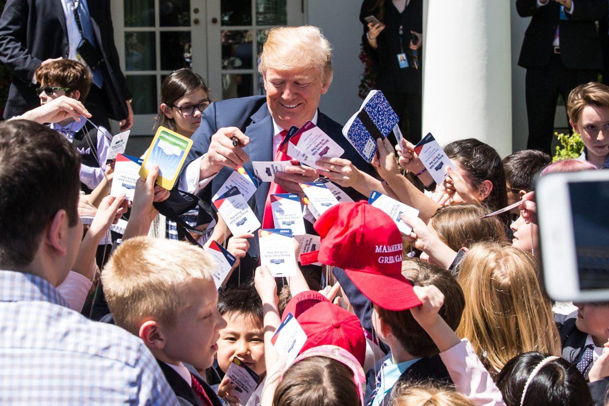 President Donald Trump signed every child's credentials in the Rose Garden during 'Take your Daughters and Sons to Work Day' at the White House in Washington on April 26, 2018. (Samira Bouaou/The Epoch Times)