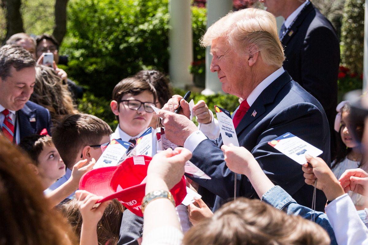 President Donald Trump signs autographs to children of press and staff in the Rose Garden during 'Take your Daughters and Sons to Work Day' at the White House in Washington on April 26, 2018. (Samira Bouaou/The Epoch Times)
