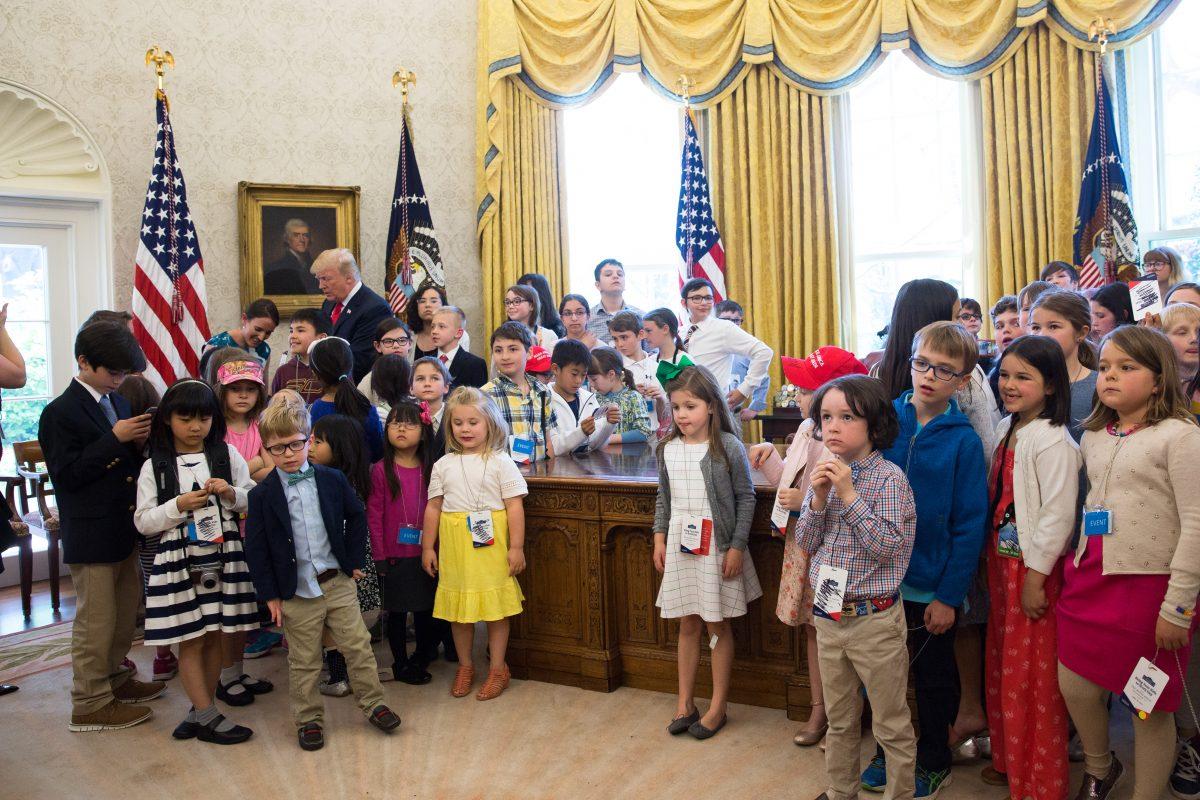 President Donald Trump is surrounded by the children of press and staff during 'Take your Daughters and Sons to Work Day' in the Oval Office at the White House in Washington on April 26, 2018. (Samira Bouaou/The Epoch Times)