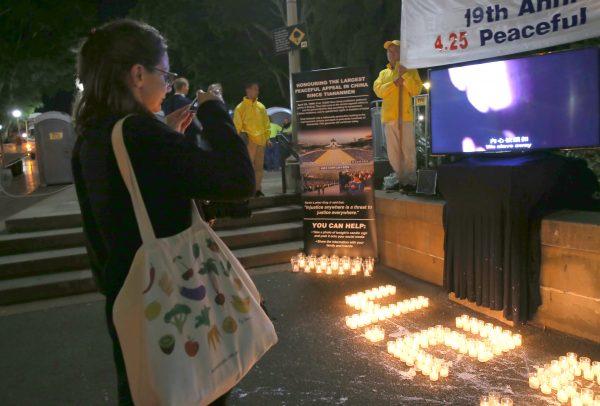 Passersby stop to support Falun Gong's peaceful appeal for freedom of belief in China by posting photos to social media. (Linda Zhang/The Epoch Times)
