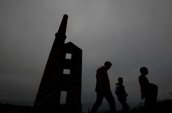 A family walk past the remains of the engine house at the Wheal Prosper copper and tin mine, on the Cornish coastline near Porthleven in Cornwall, Britain October 26, 2017. (Reuters/Toby Melville/File Photo)