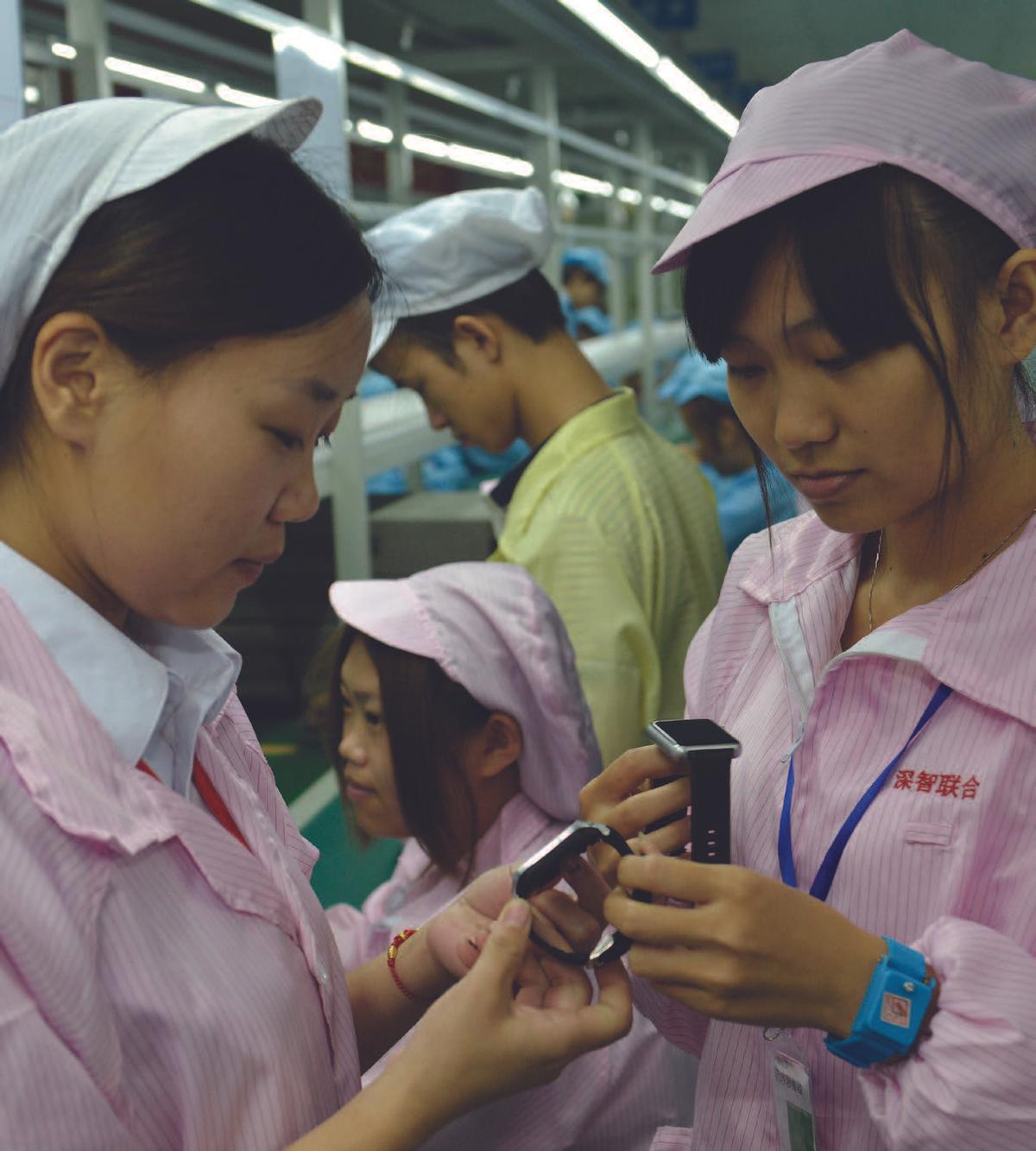 Chinese workers pose with a cheaper, local alternative to the Apple Watch in Shenzhen, in southern China’s Guangdong Province, on April 22, 2015. (STR/AFP/GETTY IMAGES)