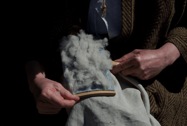 Wool being pressed onto a card, a process to thin the wool before spinning. (Channaly Philipp/The Epoch Times)